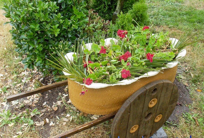 En blomsterbed lavet af et bildæk i form af en havevogn