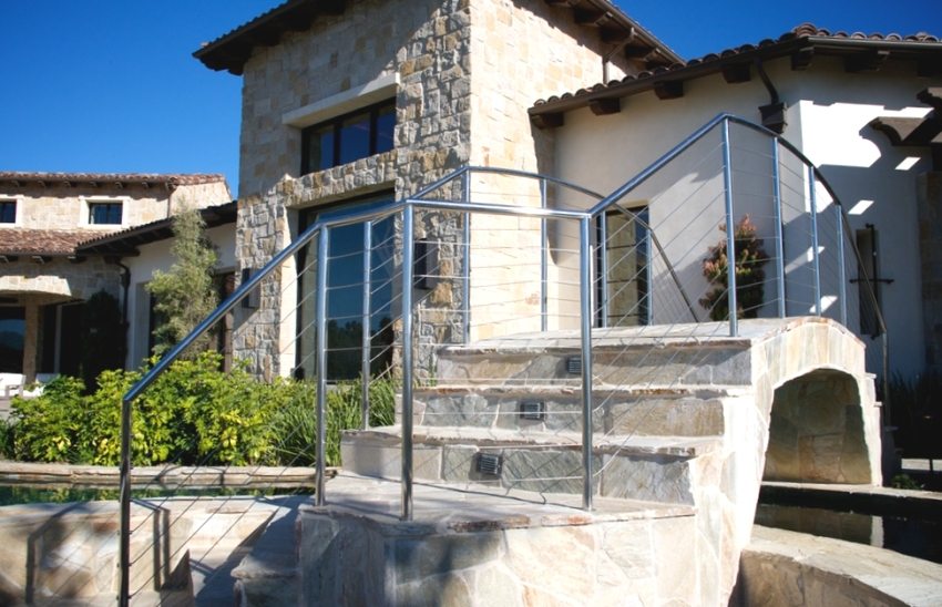 En stenbro i gården til et privat hus er dekoreret med gelænder i rustfrit stål