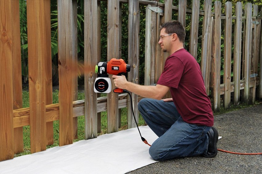 You can paint a wooden fence evenly and quickly using a spray gun